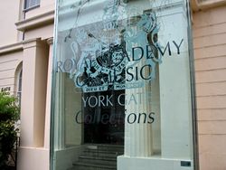 a classical building with a modern sign identifying it as the Royal Academy of Music