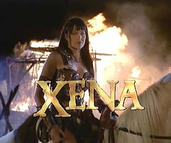 A woman in leather armor sits on horseback with flames behind her. At the bottom of the screen in capital letters is the word "Xena" in gold lettering.