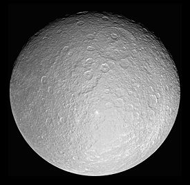 A spherical body is almost fully illuminated. The terminator is running near the top edge. The surface is covered by numerous craters. Two partially overlapping large craters can be seen above the center. One that is younger is above and to the right from the older one.