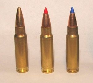 Photo of three 5.7x28mm cartridges as used in the Five-seven. The left cartridge has a plain hollow tip, the center cartridge has a red plastic V-max tip, and the right cartridge has a blue plastic V-max tip.