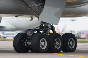 Aircraft landing gear. Six wheel gear on the ground, with attachment assembly and gear door leading up to the aircraft belly.