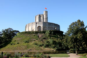 A small castle comprising a round keep surrounded by a tall encircling wall on top of a man-made hill