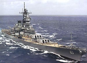 A large ship sailing on the ocean, with white tipped waves in the foreground.