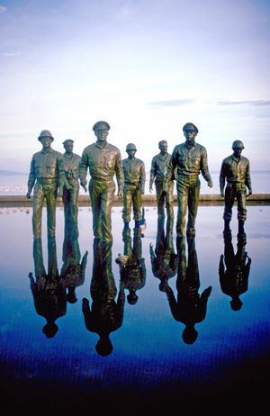 Five bronze statues of men, ankle deep in water so they look like they are perpetually wading through it.