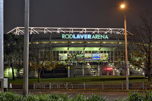 A large building, at night, with some vegetation around it, and a sign reading "Rod Laver Arena"