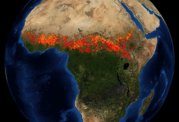 An artificially colored satellite view of Africa, with red and yellow markers where fires have been detected. A wide red band of markers runs east-west, just south of the Sahara Desert.