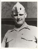 Head and shoulders of a smiling white man wearing a light-colored garrison cap and buttoned-down shirt with a bar-shaped pin on each side of the collar.