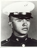 Head of a young Hispanic man wearing a white peaked cap with black visor and a dark military jacket with an eagle-globe-and-anchor pin on either side of the upright collar.