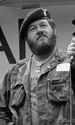 A black and white image of an older Wetzel with a beard wearing a camoflouge jacket, black beret and his Medal of Honor around his neck.