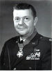 A black and white photo of a man in his military uniform. He is looking at the camera.