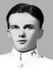 Head of a young, dark-haired man in a white military coat with bright buttons and an emblem on the collar.