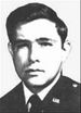 Head of a young white man with thick hair wearing a dark military jacket with a "U.S." pin on the lapel.