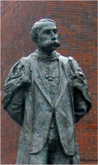 photograph of modern statue of Edwardian male figure with a large moustache in academic gown and wearing badge of the Order of Merit