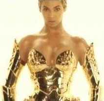 A women wearing a golden metallic corset and a pair of sleves of the same material, is standing and looking forward.