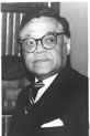 Black and white photo of an African American man in a suit wearing glasses looking to his left