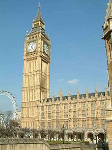 Sand-coloured building of Gothic design with large clock-tower.