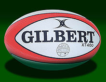 An oval shaped synthetic ball, white in colour with red trim, adorned with the manufacturers name.