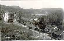 Valley landscape with houses, forest to right and lake in far background