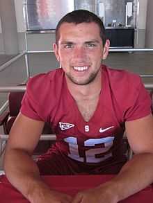 A man wearing a red jersey with the number 12 on it while sitting down.