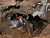 A man caving in muddy passage with helictite formations on the walls and ceiling