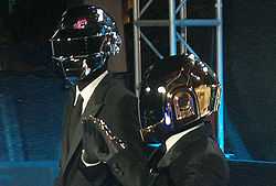 Two men wearing grey jumpsuits and robot helmets.