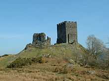 upon a grassy hillock stands two rectangular built fortifications. The one to the left is ruinous whilst the one to the right appears whole with battlements