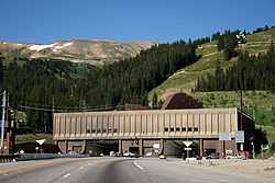 Building facing a large mountain with two openings for the traffic, visible on the roof of the building are large ventilation hoods