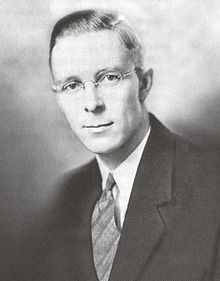 A head and shoulders shot of a young bespectacled man with short dark hair