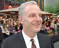 A picture of gray-haired man smilling. He wears a tuxedo and a tie.