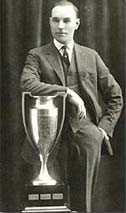 man in suit leaning on trophy in front of him