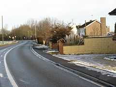 20th century suburban housing in a rural setting.  A series of small, modern, houses on the right of a twisty road, with open views to the left.