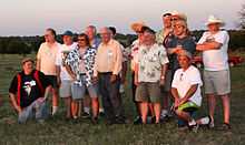 Color photograph of a group of standing men, with Glenn Lord in the center.