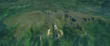 A long lightly glaciated mountain mass surrounded by vegetation.