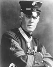 Top half of man in formal 1900s military dress, wearing a star-shaped medal on a ribbon around his neck.