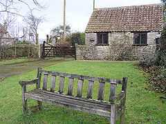 Wooden seat on grassy area with building behind