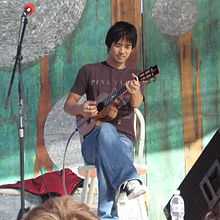 Shimabukuro seated and playing ukelele