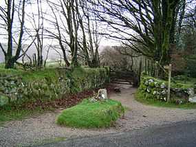 An earthen lane circles a raised grassy area containing a large stone