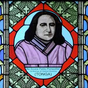 A man with shoulder-length black hair, wearing a lilac tunic, is shown in a colored glass window. In the glass beneath the picture is his name and the phrase "1st Bishop of Central Oceania (Tonga)"