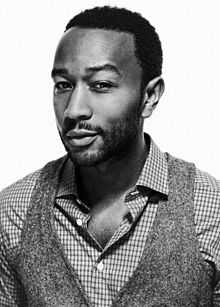 A black-and-white photograph of an African-American man wearing a polo shirt and vest.