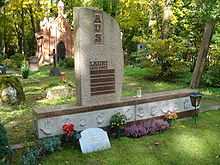 Gravestone with flowers at the base surrounded by grass