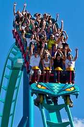 A photograph of a roller coaster train, full of passengers, on its track.