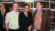 Waist high portrait of three middle aged people in the library of what could be a boat or other confined space.