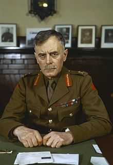 A middle-aged, moustachioed man in military garb seated at a table