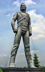 Silver-colored statue of Jackson standing up with his arms bent inward and both legs spaced apart.