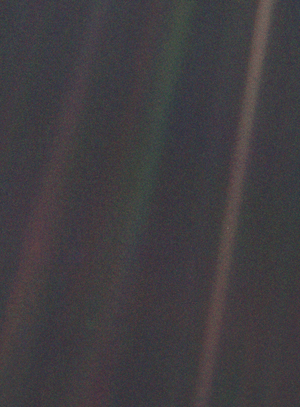 Dark grey and black static with coloured vertical rainbow beams over part of the image. A small pale blue point of light is barely visible.