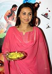 Rani Mukerji is dressed in a pink salwaar and holds a plate of porridge in her hand