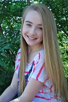 Girl with long hair smiles at the camera.