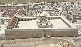 A bird's eye view of a large paved area surrounded by colonnades, with a long columned structure along the left side and, in the center of the paved area, a tall structure surrounded by an inner courtyard.