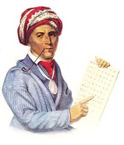 Portrait depicts a man smoking a thin pipe and pointing to an alphabet. He wears a red turban and a light blue coat.