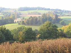 Yellow stone mansion set in parkland of fields and trees